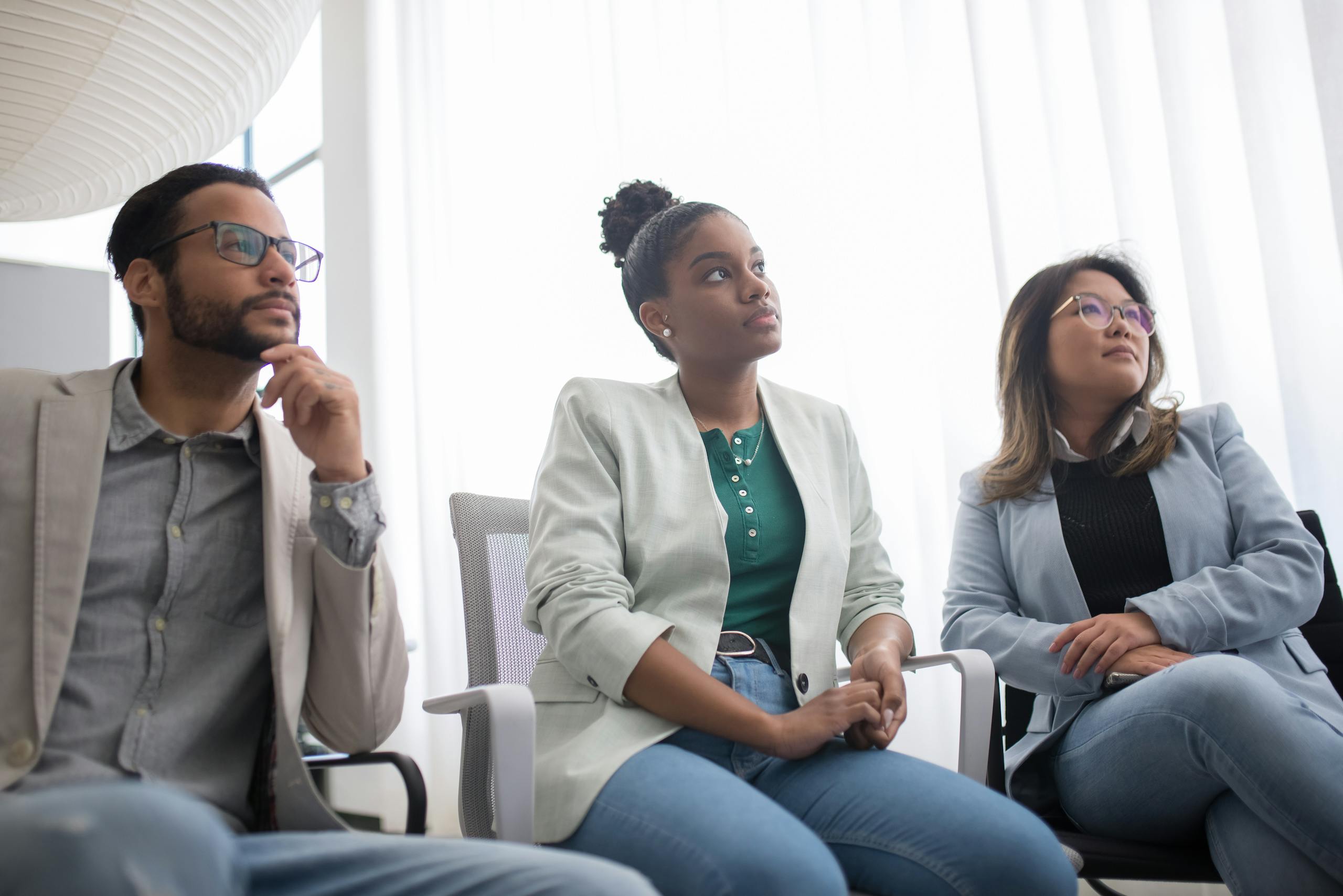 Diverse group of business professionals engaged in a serious meeting, showcasing teamwork and modern office culture.